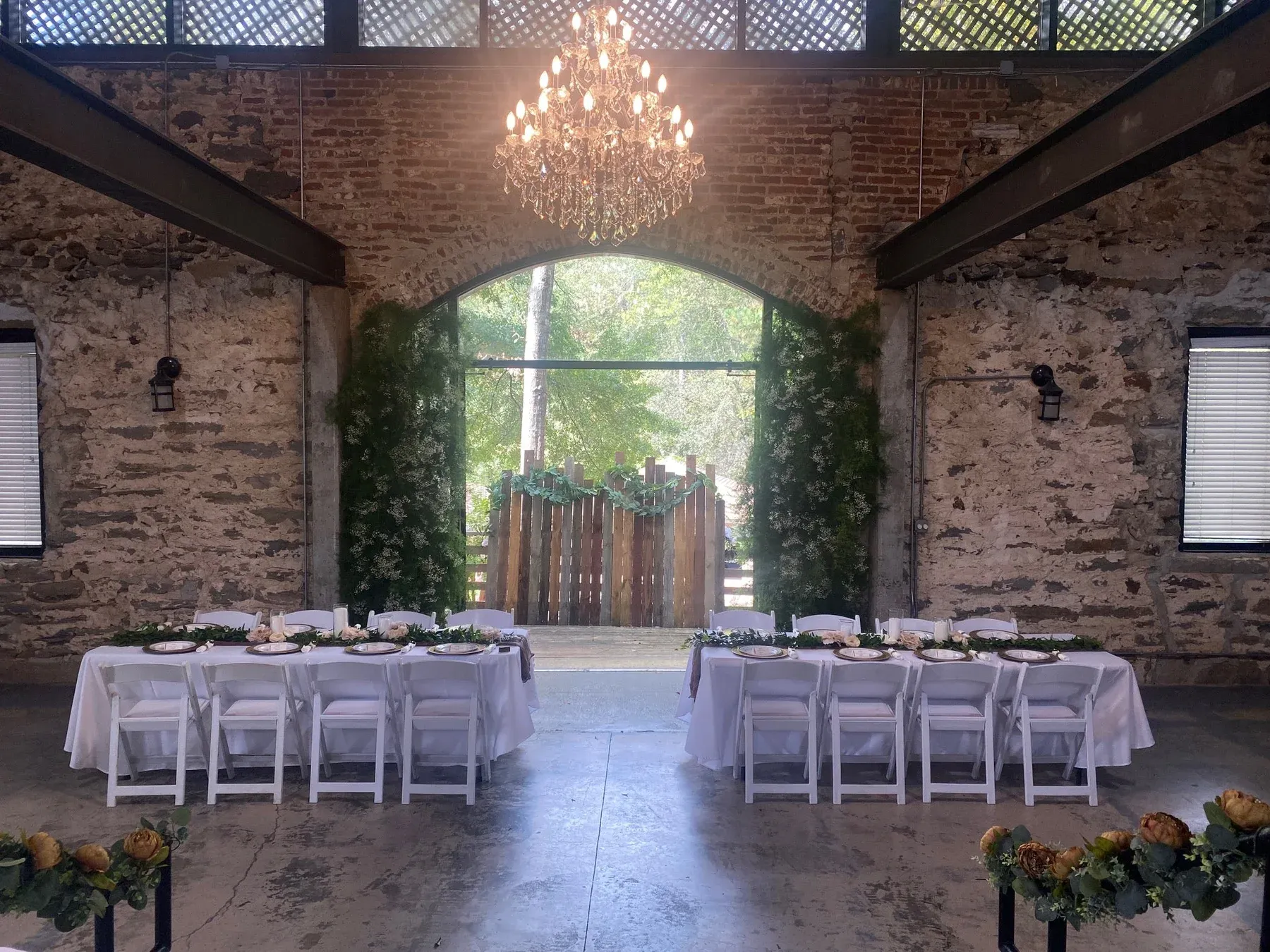 Brick reception room with white chairs and linen-covered tables