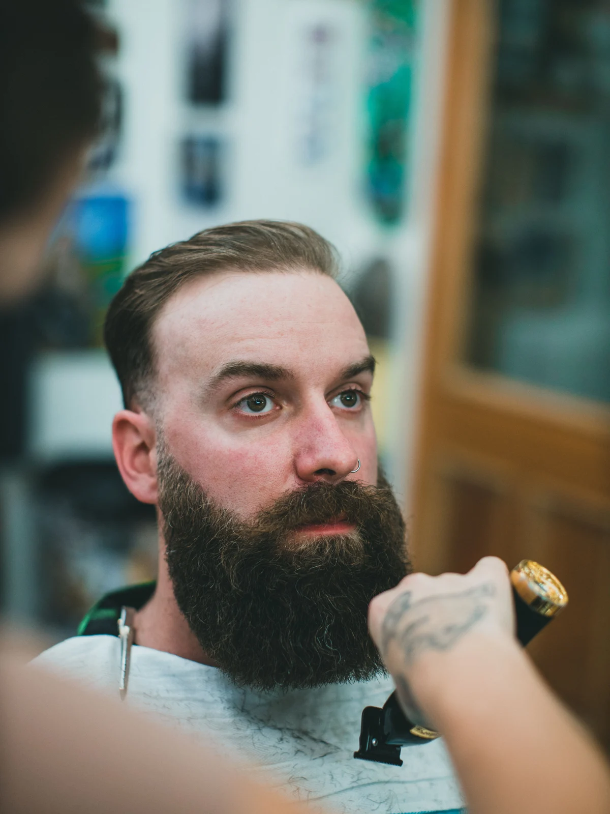 Stock photograph of a bearded client receiving a precision haircut