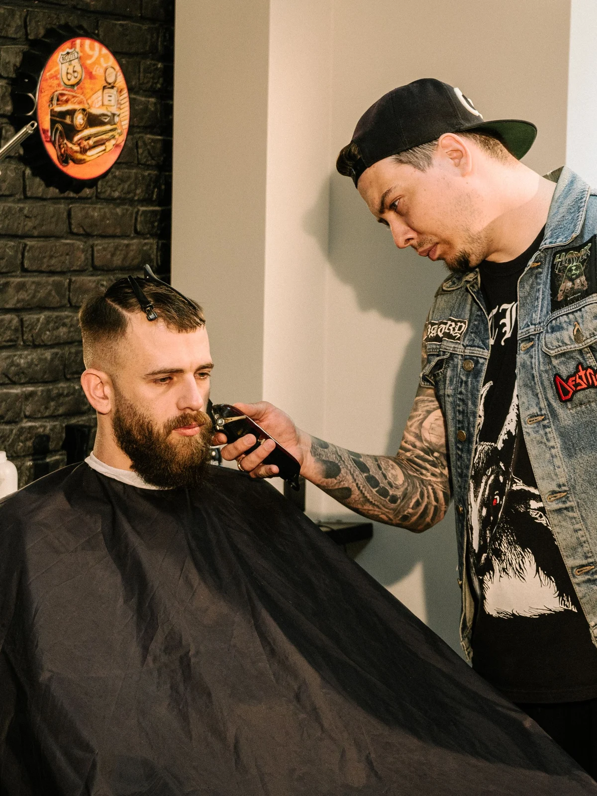 Stock photograph of a barber cutting a client’s hair beside a brick wall