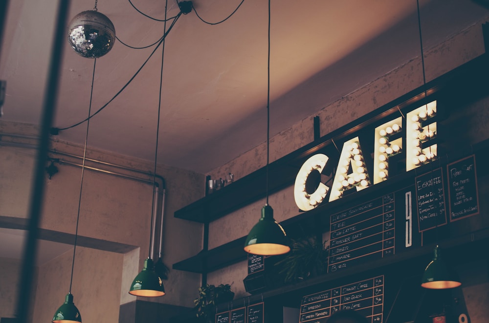 Warm pendant lights and an illuminated café sign above a coffee counter